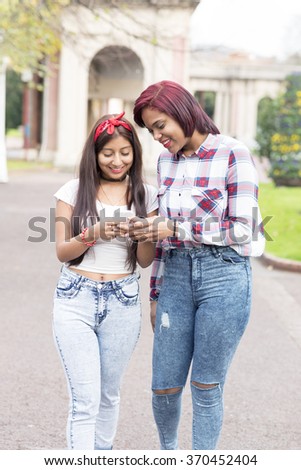 Two smiling woman friends sharing social media in a smart phone.