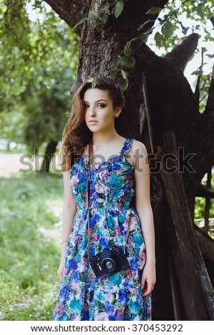 young beautiful girl posing on the street, in a beautiful blue dress from her vintage retro camera, makes beautiful pictures outdoor portrait
