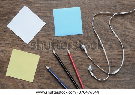 Work space table with paper, pencil, and headphone on wood background