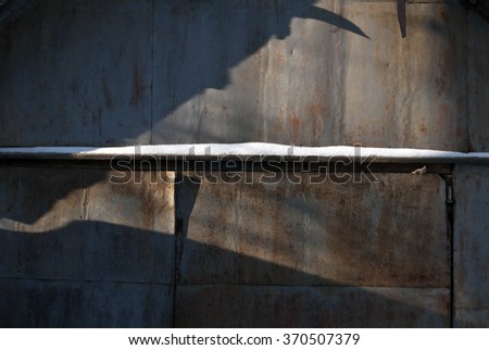 Metal wall with shadows and snow. Architectural background.