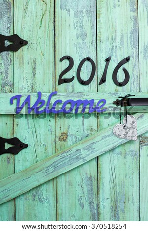 Welcome sign, year 2016 and silver tin heart hanging on antique rustic mint green wood door
