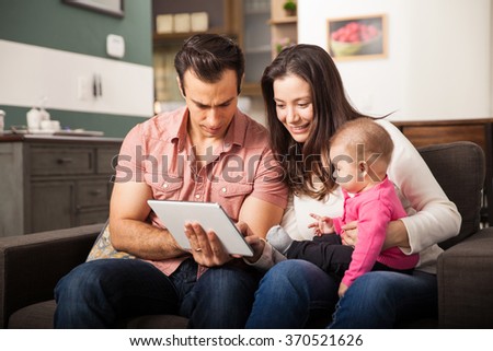 Good looking young parents showing some games and cartoons to their baby girl on a tablet computer