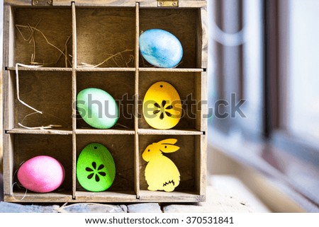 Easter eggs and decorations in wooden box divided with shelves