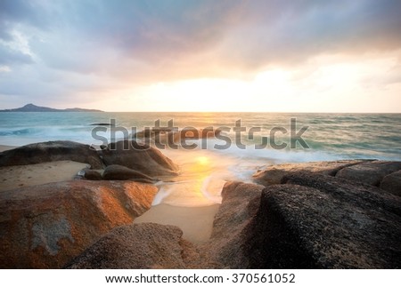 Colorful sunrise over the sea and rocks - long exposure.