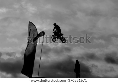 Man doing trick by motorbike. Flying moto freestyler. Black and white photo