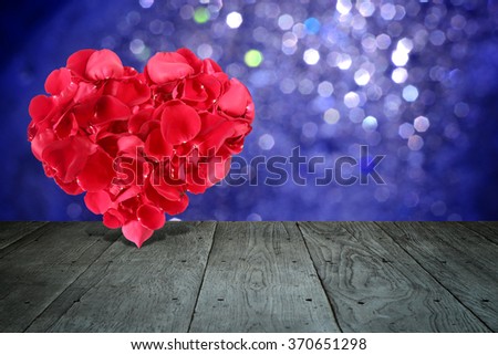 Valentine composition with heart shape made out of rose petals on wooden deck table with bokeh
