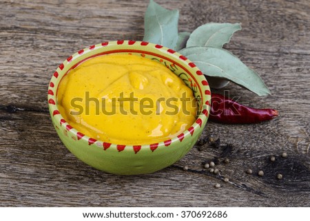 Curry sause with red pepper and coriander seeds on wood background