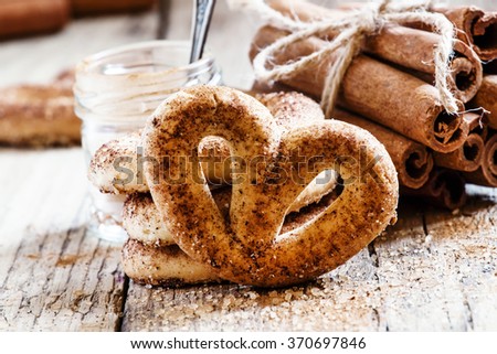 Pretzels with ground cinnamon, cinnamon sticks, brown cane sugar on the old wooden background, selective focus
