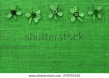 St Patricks Day top border of handmade paper shamrocks over a green burlap background
