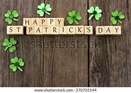 Happy St Patricks Day wooden blocks with handmade paper shamrocks over a rustic wooden background