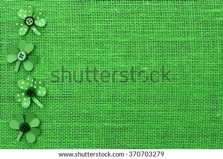St Patricks Day side border of handmade paper shamrocks over a green burlap background