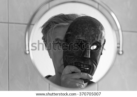 Man with mask looks in the mirror.