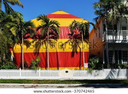 A residential house covered with a red and yellow canvas tent while being fumigated for termites.