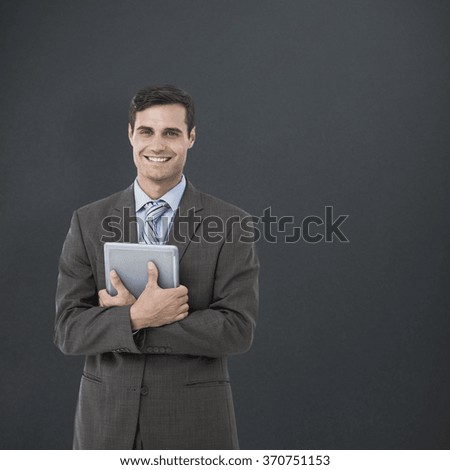 Portrait of smiling businessman holding digital tablet against grey background