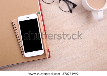 top view blank screen smartphone on book and glasses on wooden background