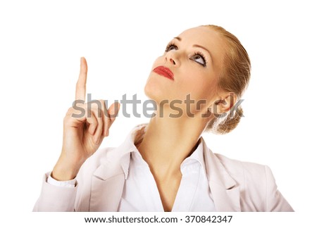 Young smiling business woman pointing up