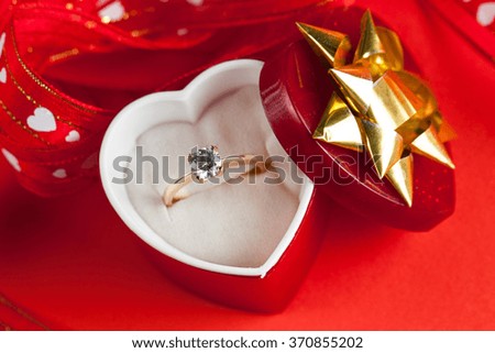 close-up image of wedding rings in a gift box on red background