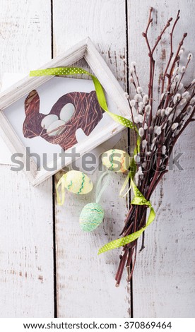 Quail eggs and willow,the picture of the rabbit in wooden frame,Easter symbol on a light background.selective focus.