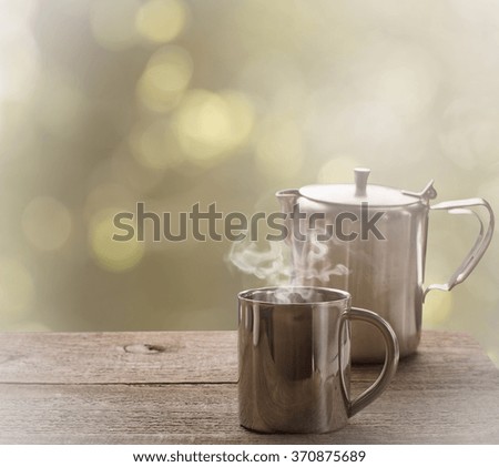 Tea time, stainless steel tea cup and tea pot over wooden table outdoors