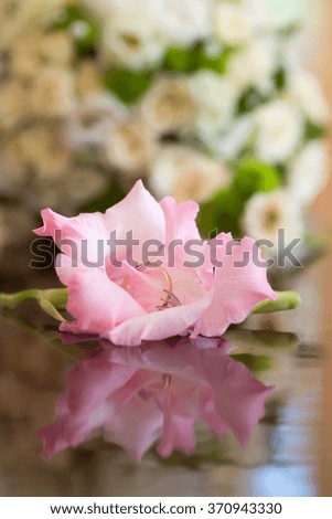 Pretty golden yellow wedding female ring symbol of marriage inside light pink beautiful gladiolus flower fashion design in background of pretty bouquet closeup studio, vertical picture 