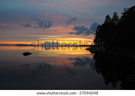The final stage of a cloudy sunset above the huge lake in Karelia region. The picture is colorful and relaxing.