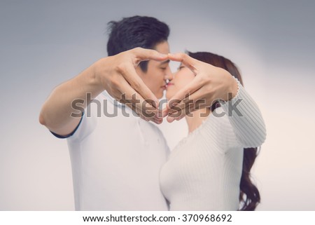 Vintage color of Hands in shape of love heart. Closeup of couple making heart shape with hands. Attractive boy and girl posing and kissing 