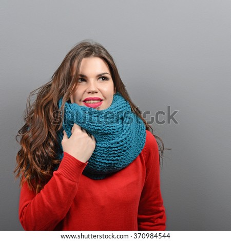 Portrait of young beautiful woman in winter clothes against gray background
