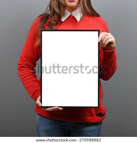 Woman holding empty frame with space for your advertisement against gray background
