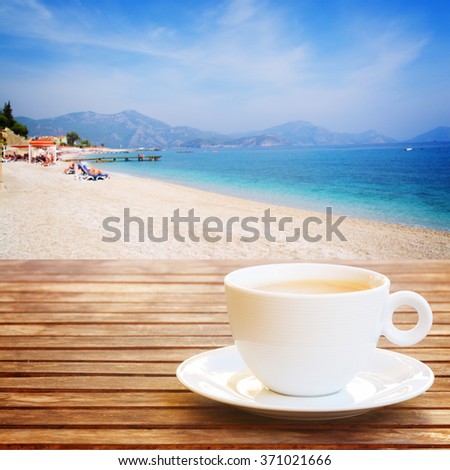 white cup of coffee on wooden table over summer background, retro toned