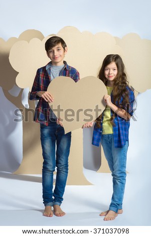 Boy and girl holding a cardboard heart. Love concept