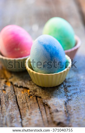 Colorful Easter eggs in egg cups on a shabby wooden background