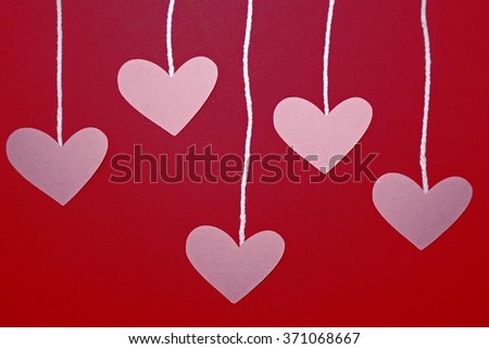 Hearts hanging by string on a red and purple background, can be used for a Valentine's Day or Mother's Day project