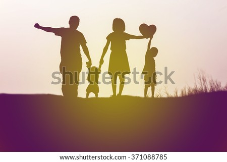 Silhouettes of happy parents having good time with their little children