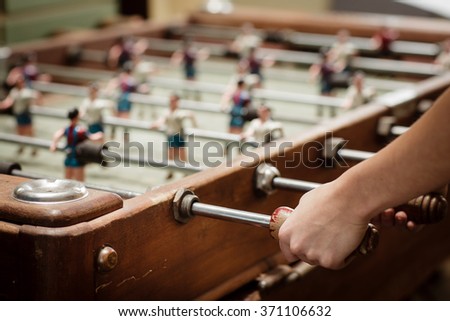 Detail of girl's hands playing the foosball vintage table match. Color toned image. Concept photo of leading the company. Royalty-Free Stock Photo #371106632
