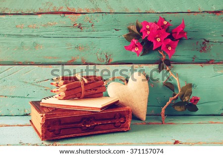 vintage notebook and stack of wooden colorful pencils on wooden texture table next to purple bougainvillea flower
