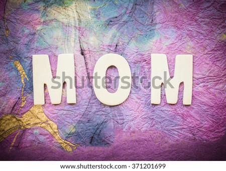 Word "Mom" design by white letterpress on colorful  paper background