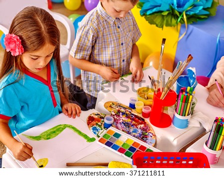 Little girl and boy  painting picture by brush on table in  kindergarten . 