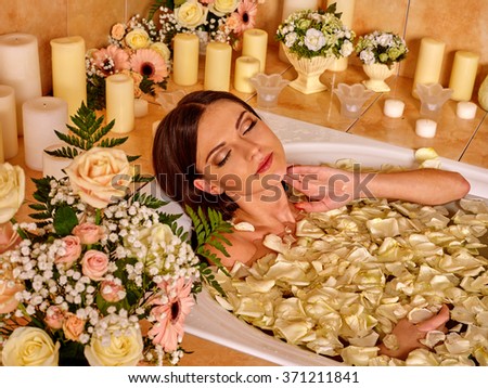 Woman applying luxury bath with rose petals at bathroom.