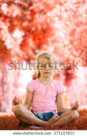 Pretty blonde girl meditating in yoga pose in park
