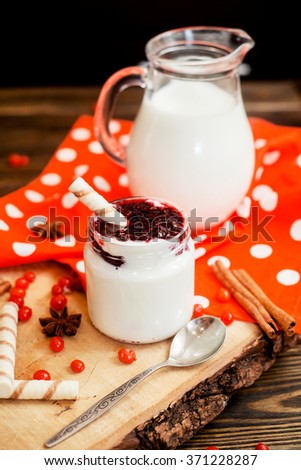 
healthy breakfast , pudding or yogurt with strawberry and cherry jam , milk , sweet tubes , berries and cinnamon on a wooden background