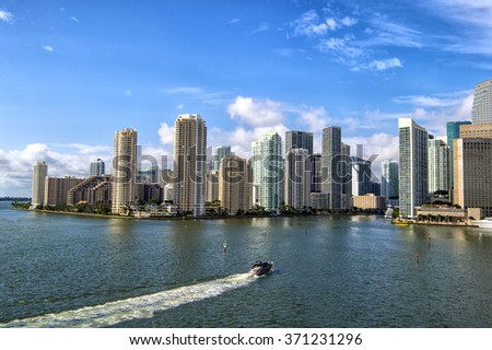 Aerial view of Miami skyscrapers with blue cloudy sky, boat sailing next to Miami downtown, horizontal picture