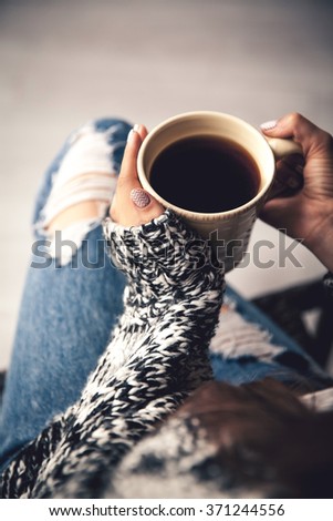 Girl's hands holding a cup of coffee, ripped jeans. nails, manicure, fashion