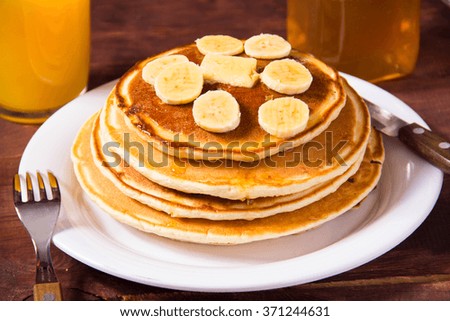 Pancakes with bananas and orange juice on a wooden background