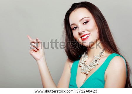beautiful young woman pointing her finger towards blank space
