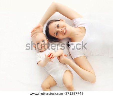 Happy smiling mother and baby lying on bed at home, top view