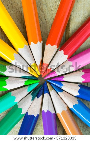 Macro circle of colored pencils on wood background