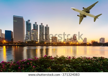 Modern building with flower and airplane under the sky at twilight in Bangkok, Thailand.