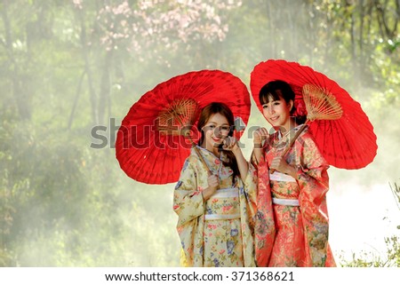 Couple asian women wearing traditional japanese kimono and red umbrella in the himalayan sakura garden,Thailand. Royalty-Free Stock Photo #371368621