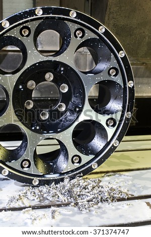 Car alloy black new rim die mounting in milling and lathe cnc machine. Front view of working process. Mechanical engineering and metalworking industry. Indoors vertical image.