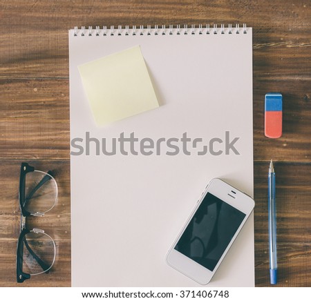 Glasses, paper, phone and pen on the wooden table